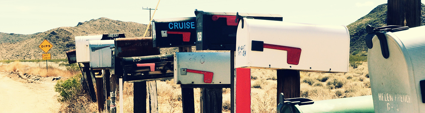 A group of mailboxes lined up along a dirt road.