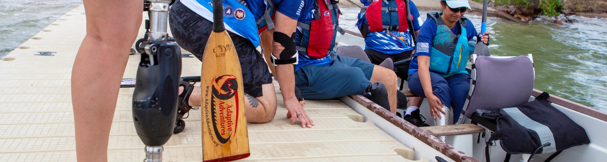 People in personal flotation devices loading into a boat from a dock at a lake