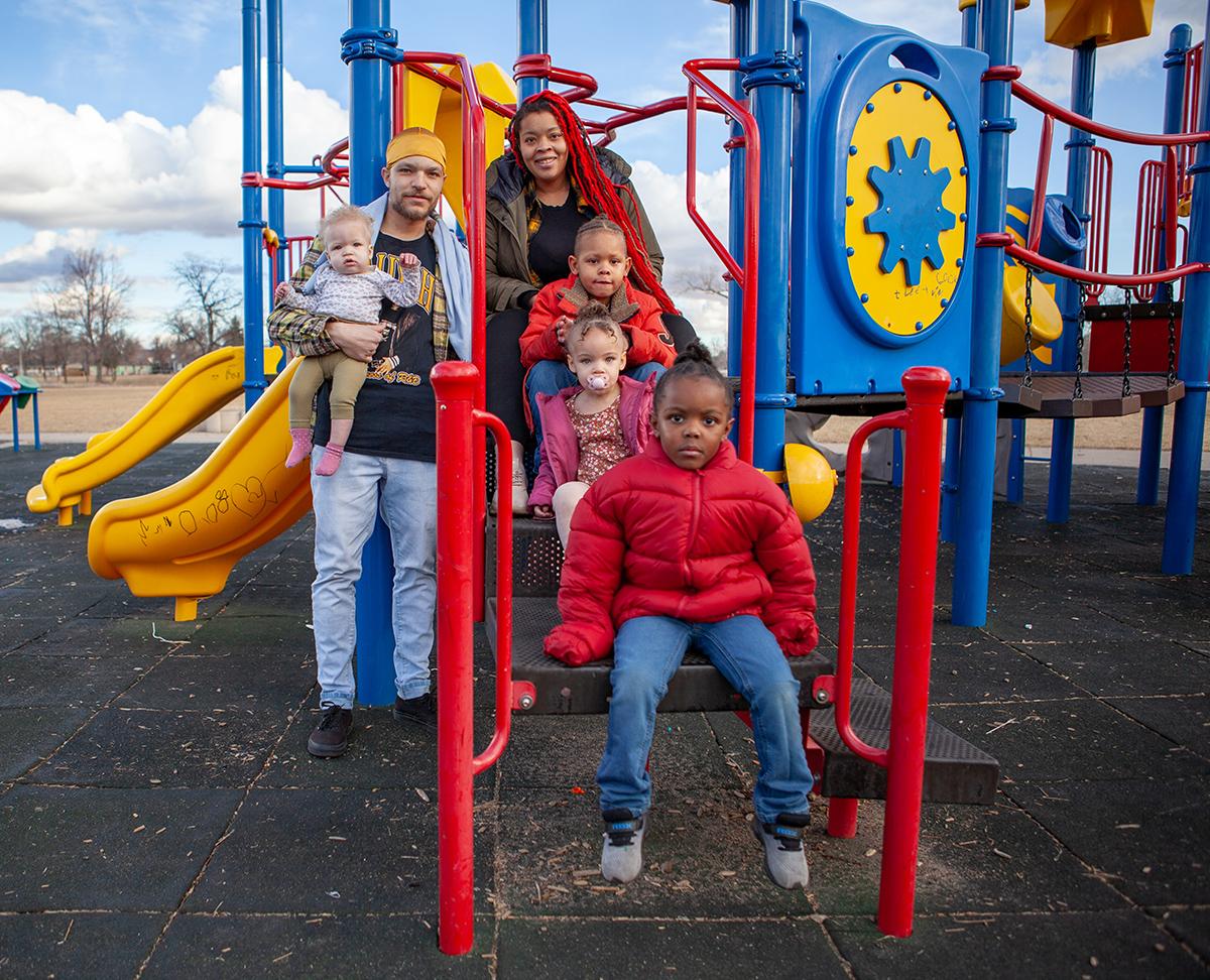 Charlie Guy, top center, and family sitting on playground equipment