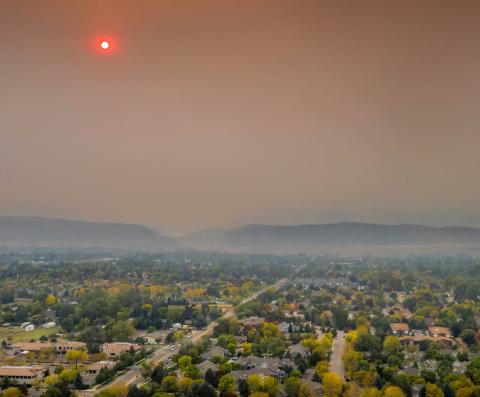 The sun glows red as smoke from the Cameron Peak fire blankets Fort Collins