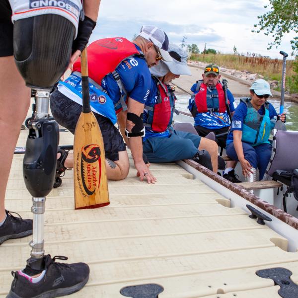 Marc Hoffmeister assists Bill Drummond into in the Team Blue dragon boat while Gary Verrazono and Honey Hendesi adjust their positions.